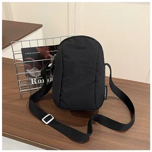 Close-up of black nylon crossbody bag with LANWEIER logo on a dark wooden table