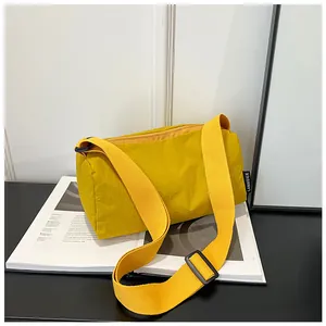 Detail of yellow nylon cylinder crossbody bag with adjustable wide strap on magazine