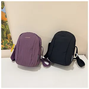 Close-up of purple and black nylon crossbody bags with subtle crinkled texture