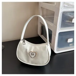 Detailansicht einer weißen Handtasche mit Herzschnalle, Strasssteinen und Schleifenmuster