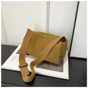 Detail of nylon cross-body bag with woven label and adjustable canvas shoulder strap