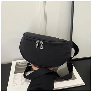 Detail of black waterproof nylon crescent bag with silver zippers and adjustable strap
