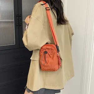 Petit sac à bandoulière orange minimaliste pour femme avec sangle réglable et logo de marque