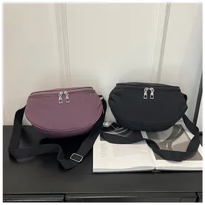 Detail of adjustable nylon strap and dual silver zippers on minimalist crescent bags