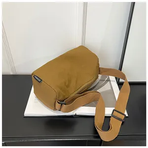 Detail view of caramel nylon shoulder bag with adjustable strap and brand logo tag