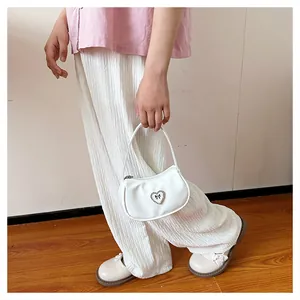 Detail einer weißen Mini-Handtasche mit Herz-Schnalle aus Kristall an einem stilvollen Model