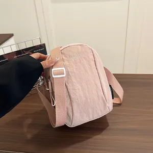 Pink waterproof nylon crossbody phone bag with adjustable strap and casual sporty style