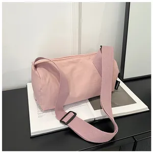 Detail of light pink nylon boston bag featuring adjustable strap and black side brand tag