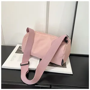 Detail of pink nylon barrel bag with woven strap on a magazine in a minimalist setting