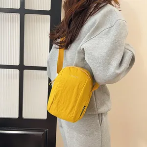 Waterproof yellow nylon crossbody bag with adjustable strap worn by model for casual use