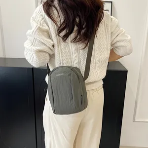 Olive green nylon crossbody phone bag for women worn with casual white knitwear