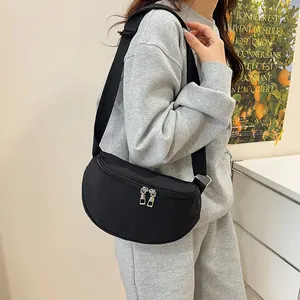 Minimalist black crescent crossbody bag with nylon strap shown on model in modern setting