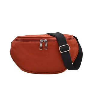Burnt orange nylon crescent crossbody bag with double zippers and adjustable strap