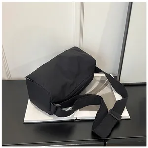 Detail of minimalist black nylon cylinder bag with wide strap on magazine