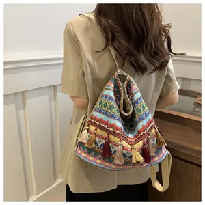 Detailed view of colorful Bohemian embroidery patterns and soft cotton tassels on the bag