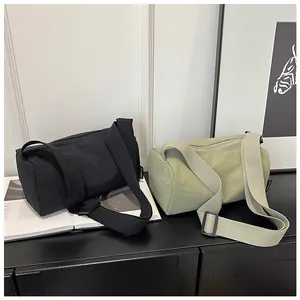 Detail of minimalist nylon barrel bags in black and light green with wide straps