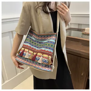 Close-up of bohemian woven shoulder bag with colorful geometric patterns and fringe