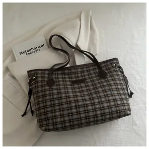 Detail of tweed checkered tote bag featuring brown leather handles and drawstring sides