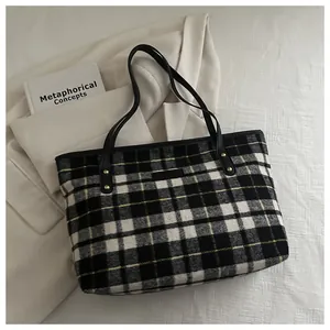 Close-up of black and white plaid tweed tote bag with elegant gold rivet details