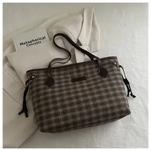 Detailed side view of vintage plaid tote bag with brown leather handles and side drawstring