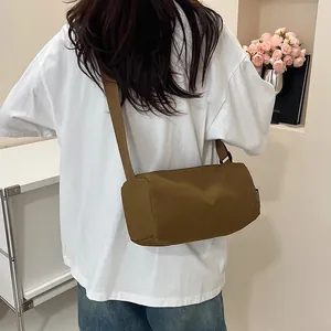 Brown nylon crossbody cylinder bag with adjustable strap and minimalist sporty design
