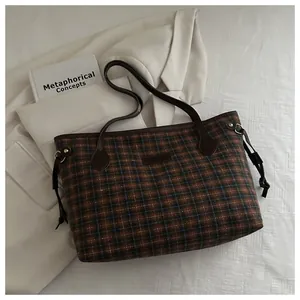 Detail of plaid tote bag featuring brown wool fabric, leather straps and drawstring accents