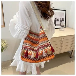 Detail view of woven bohemian shoulder bag featuring vibrant orange tassels and wave patterns