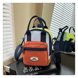 Detail of multi-color crossbody bag featuring double zippers and smile logo on nylon