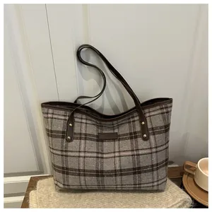 Detail of the large grey plaid tote bag with premium leather straps and gold rivets