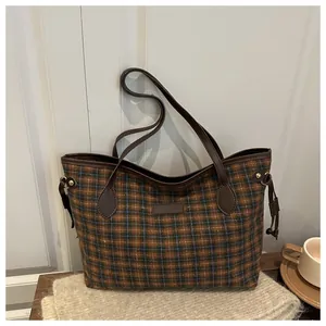 Close-up of brown and blue plaid tote bag showing textured fabric and leather detail