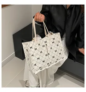 Detailansicht der weißen gesteppten Cord-Tragetasche mit schwarzen Schleifen und Taschen