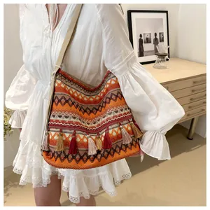 Close-up of bohemian knitted shoulder bag with colorful tassels and geometric patterns