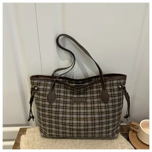 Macro shot of plaid wool fabric texture and brown leather trim on a large tote bag