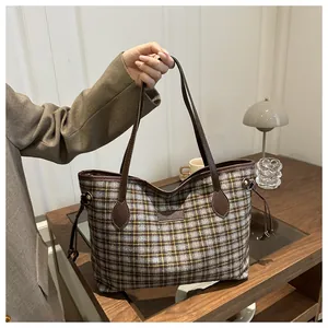 Detail of plaid tote bag with brown leather handles and side drawstring accents