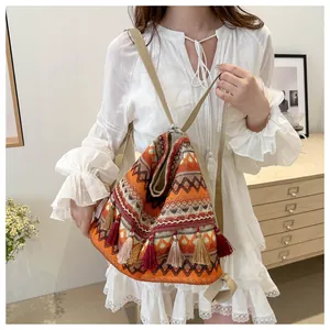 Detail of bohemian woven backpack featuring vibrant orange patterns and colorful tassels