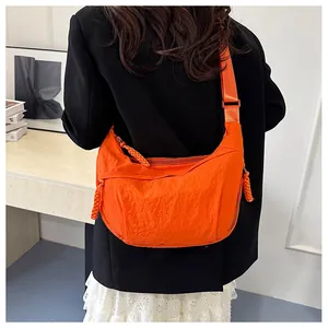 Close-up of bright orange nylon crescent bag showing water-resistant texture and wide strap