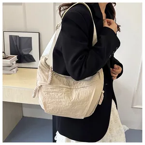 Model wearing a minimalist cream crescent nylon crossbody bag with knot details