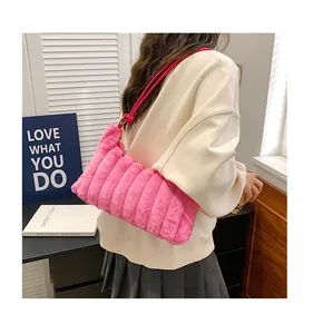 Detail of plush pink faux fur shoulder bag with ruched texture worn by a model