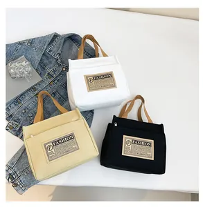 Vue détaillée de sacs fourre-tout en toile vintage blancs, beige et noirs avec anses brunes