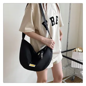 Detail view of a black nylon crescent crossbody bag with a detachable round coin purse