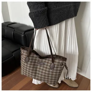Detail of vintage plaid tote bag with brown leather straps and side drawstring design