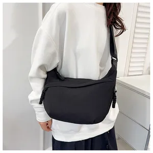 Detailed back view of a black nylon crossbody crescent bag on a minimalist model outfit