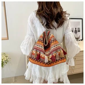 Detail of bohemian ethnic backpack featuring vibrant orange geometric patterns and colorful tassels