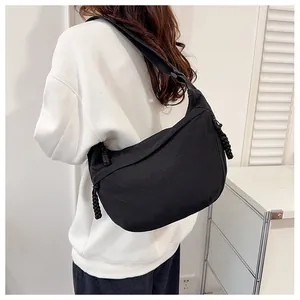 Close-up of black nylon dumpling bag featuring an adjustable strap and braided zipper pull