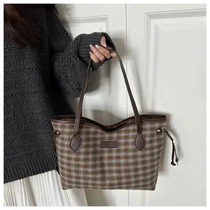 Detail view of retro plaid tote bag showing leather strap and drawstring closure