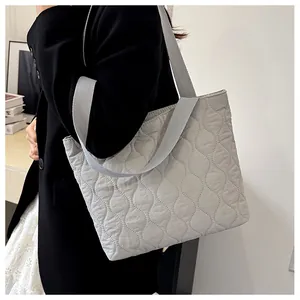 Close-up of wavy quilted tote bag in light grey with durable woven fabric handles