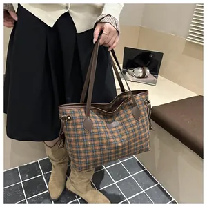 Detail view of large plaid tote bag with brown leather handles and woven texture
