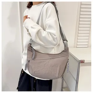 Detail of grey nylon crescent bag showing braided zipper pull and wide adjustable strap