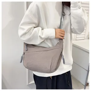 Detail of grey nylon crescent bag with woven rope accents and adjustable strap worn by model