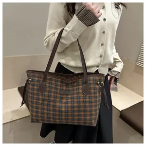 Detail of vintage plaid tote bag with brown leather straps and drawstring accents